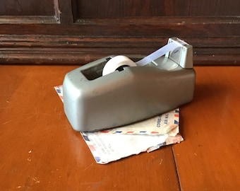 MCM metal tape dispenser, sleek body, classic design an office ‘staple’. All metal body for one hand use.
