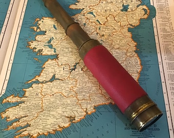 Vintage brass telescope, extending spy glass with dark red leather barrel cover. Fully extendable maritime oceangoing sea travel.
