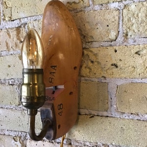 May include: A wooden shoe-shaped lamp with a light bulb and a metal arm. The shoe is labeled "8AA" and "48".