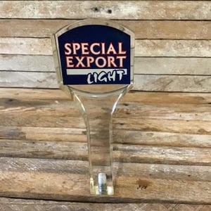 May include: A clear plastic beer tap handle with a blue and red label that says "Special Export Light".