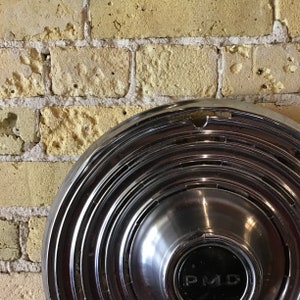 Large vintage Pontiac Motor Division hubcap polished chrome with PMD black center insignia. Centric circle design.