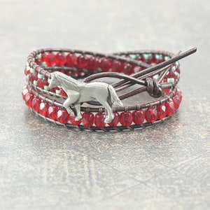 May include: A brown leather wrap bracelet with red and turquoise beads and a silver horse charm.