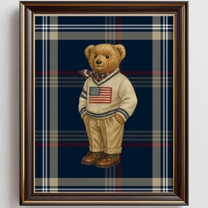 May include: Framed print of a teddy bear in a cream sweater with an American flag, khaki trousers, and brown shoes. Set against a navy blue plaid backdrop, the artwork is enclosed in a dark brown frame. The image has a classic aesthetic.