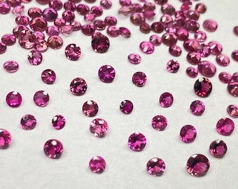 May include: A collection of round, faceted gemstones in varying shades of pink and magenta. The gemstones are scattered across a white surface, with a range of sizes visible. The light catches the facets, creating a sparkling effect. Ideal for jewelry making.