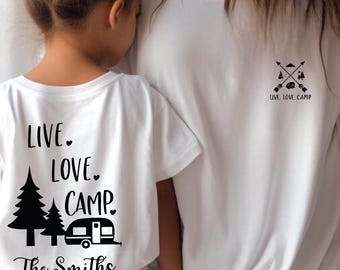 May include: White t-shirts with black graphics. One shirt features the text "LIVE. LOVE. CAMP." with a camper and trees, and the family name. The other shirt has crossed arrows, trees, and the text "LIVE. LOVE. CAMP."