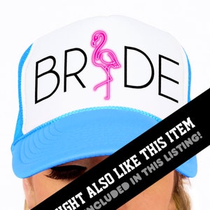 May include: White trucker hat with a blue brim. The hat has the word "BRIDE" in black text with a pink flamingo graphic in the middle.