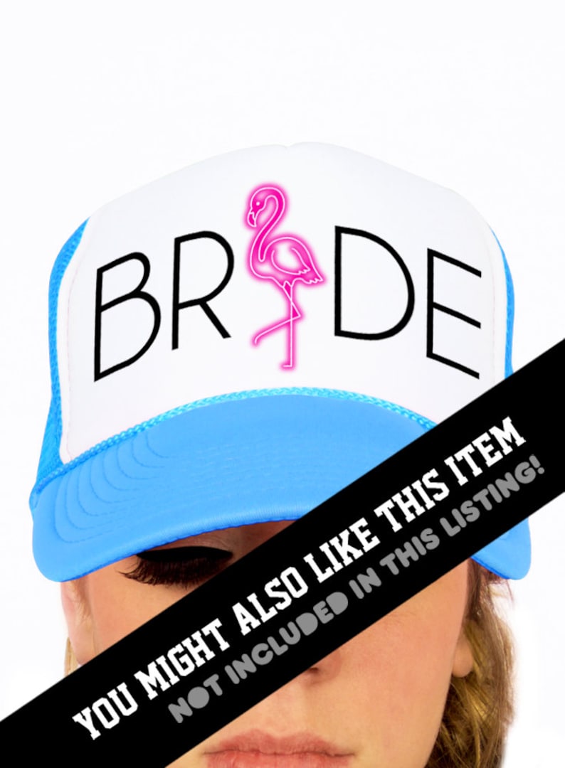 May include: White trucker hat with a blue brim. The hat has the word "BRIDE" in black text with a pink flamingo graphic in the middle.