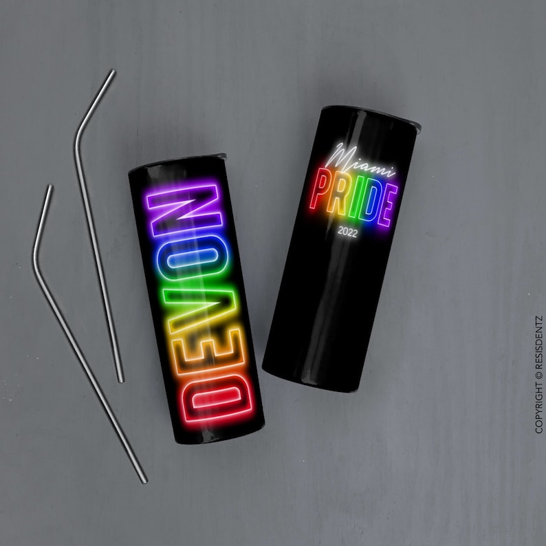 K&ouml;nnte beinhalten: Zwei schwarze Edelstahlbecher mit Regenbogen-Neon-Designs. Ein Becher sagt "DEVON" und der andere sagt "Miami Pride 2022".