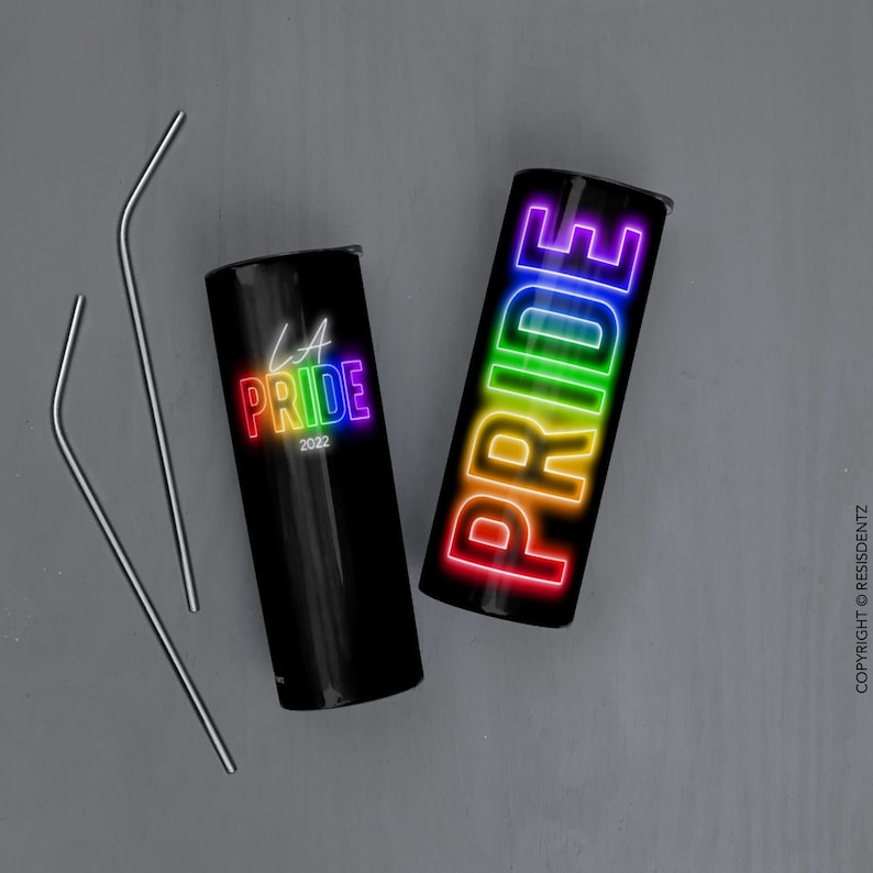K&ouml;nnte beinhalten: Zwei schwarze Edelstahlbecher mit Regenbogen-Pride-Designs. Ein Becher sagt "LA Pride 2022" und der andere sagt "PRIDE" in Regenbogen-Neon-Buchstaben.
