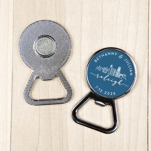 May include: Two silver bottle openers. One has a magnetic back and a textured surface. The other has a blue circular design with the names "Bethanny & Julian", the city "Raleigh", and the date "7.12.2026" in white.