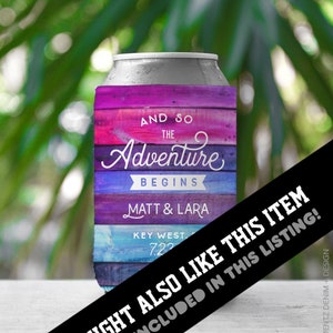 May include: A can cooler with a colorful, rustic wood-grain design. The text "AND SO THE Adventure BEGINS" is displayed, along with names and a date. The background is blurred green foliage.