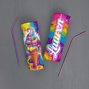 May include: Two colorful insulated tumblers with rainbow designs and matching straws. One tumbler features a psychedelic ice cream cone, the other has the name "Lauren" in a rainbow font. The straws and tumblers have a metallic finish.