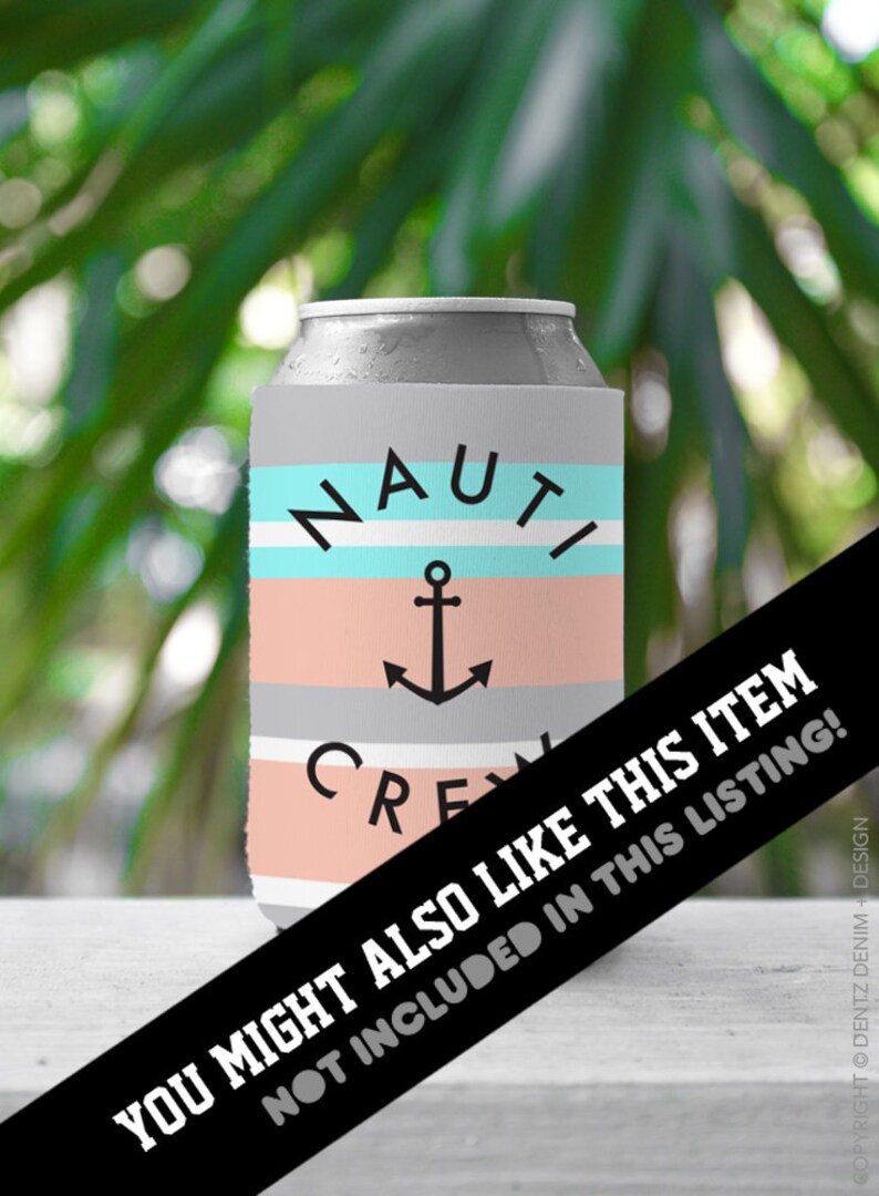 May include: A gray can cooler with the words "NAUTI CREW" and an anchor graphic. The cooler has horizontal stripes in light blue, peach, and gray. The background is blurred green foliage.