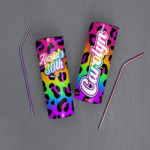 May include: Two stainless steel tumblers with rainbow leopard print design. One tumbler has the text "Alexia's 30th" and the other has the name "Carolyn". Two rainbow-colored straws are also included.