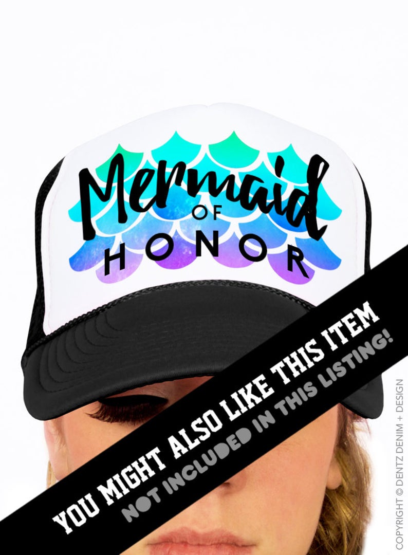 May include: A white trucker hat with a black brim and mesh back. The hat features the text "Mermaid of Honor" in black script, with a mermaid scale design in shades of blue, green, and purple.