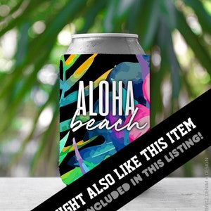 May include: A silver can cooler with the words "ALOHA beach" in white, set against a vibrant tropical design of leaves and flowers in shades of blue, pink, and yellow. The background is blurred green foliage.