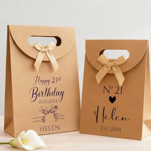 Pode incluir: Duas sacolas de presente de papel marrom com al&ccedil;as e la&ccedil;os. Uma sacola diz "Happy 21st Birthday" com uma data e um nome. A outra sacola tem "N 21" com um cora&ccedil;&atilde;o, um nome e o ano de 2004.