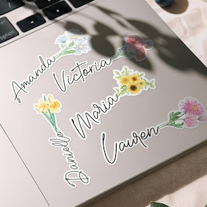 Könnte beinhalten: Eine Sammlung von Blumenaufklebern mit Namen in eleganter Schreibschrift. Die Aufkleber zeigen Aquarellillustrationen verschiedener Blumen, darunter Gänseblümchen, Sonnenblumen und rosa Chrysanthemen. Namen sind Amanda, Victoria, Maria, Lauren und Danielle.