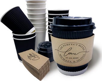 May include: An assortment of disposable coffee cups and accessories. Includes black corrugated cups, white paper cups, black lids, and brown cup sleeves. One cup sleeve features the text "The Perfect Blend Love Michael & Olivia 07.23.2026".