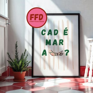 Könnte beinhalten: Gerahmter Kunstdruck mit dem Text "CAD É MAR A?" in Grün, mit einem stilisierten Arm und Fragezeichen. Das Kunstwerk hat einen schwarzen Rahmen und befindet sich auf einem weißen Hintergrund mit vertikalen beigen Streifen. Ein rosa Kreis mit "FFD FUNNY FOCAIL DESIGN" befindet sich oben links.