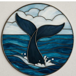 May include: Circular stained glass artwork depicting a whale's tail submerging into the sea. The design uses various shades of blue for the water and whale, with white clouds and a silver metal frame. The text "Artkilyy Design" is at the top.