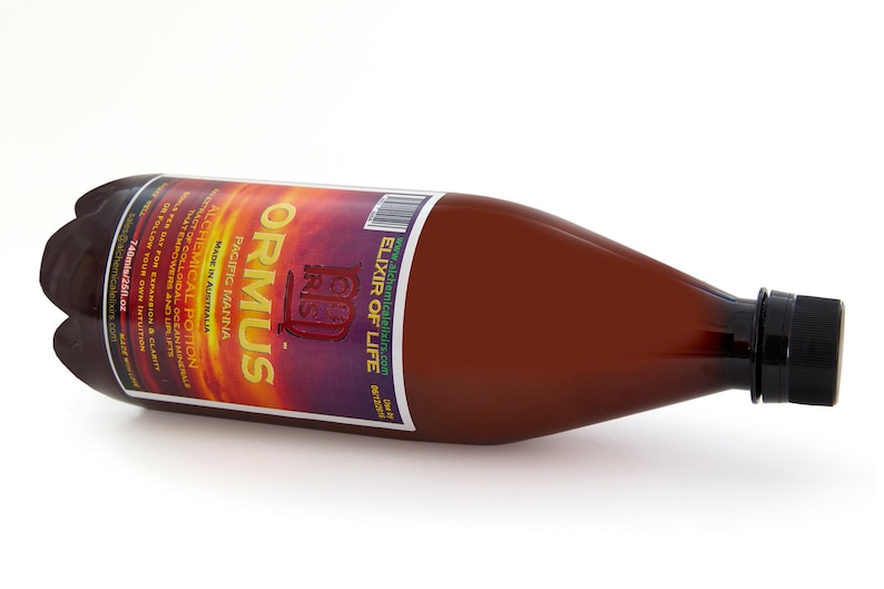 K&ouml;nnte beinhalten: Eine braune Glasflasche mit schwarzem Verschluss, beschriftet mit "ORMUS Elixir of Life", mit dem Text "Pacific Manna" und "Alchemical Potion" auf dem Etikett.