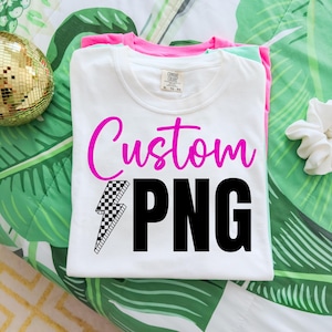May include: A stack of folded white t-shirts with the words "Custom PNG" in pink and black. A checkered lightning bolt graphic is below the word "Custom". The shirts are on a green and white patterned surface.