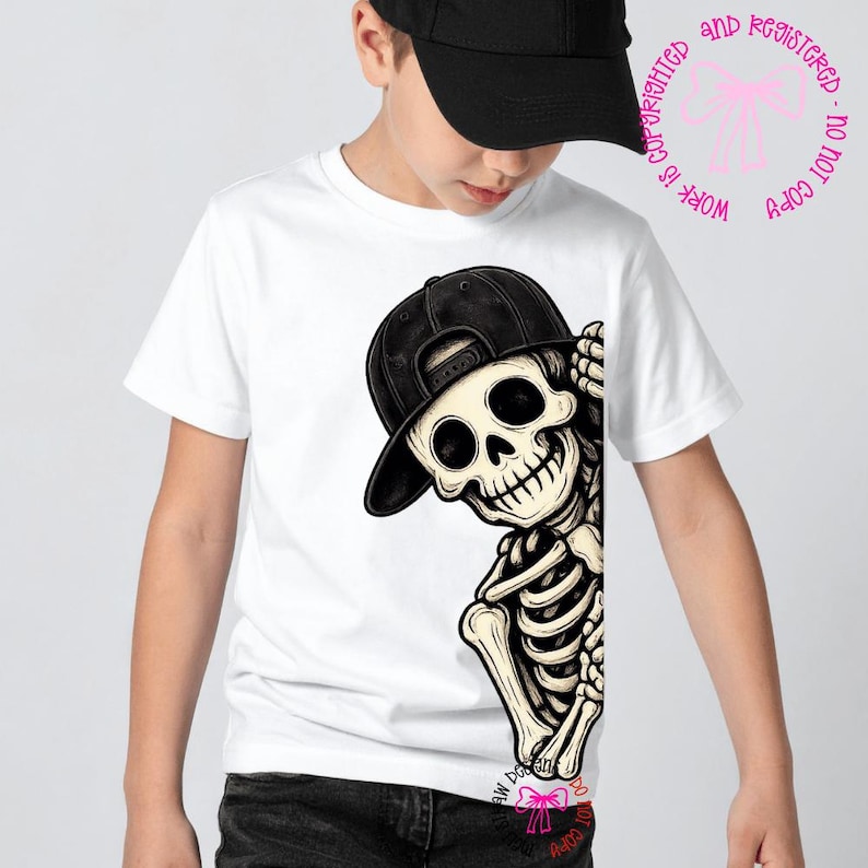 Op de afbeelding: Een wit T-shirt met korte mouwen en een grafische illustratie van een skelet met een zwarte honkbalpet. Het skelet bevindt zich aan de rechterkant van het shirt en lijkt achter de rand vandaan te komen met een hand bij het hoofd.
