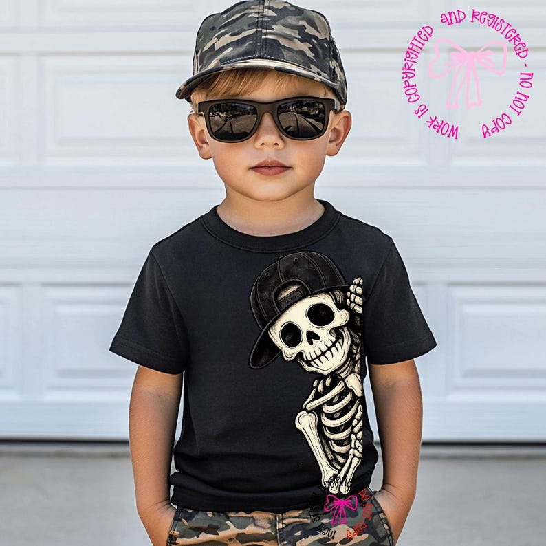 Op de afbeelding: Een zwart T-shirt met korte mouwen en een afbeelding van een skelet met een zwarte honkbalpet. Het skelet bevindt zich aan de rechterkant van het T-shirt. Het T-shirt wordt gedragen met een camouflage honkbalpet en een zwarte zonnebril.
