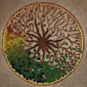 Puede incluir: Dise&ntilde;o circular bordado de un &aacute;rbol con ramas de diferentes colores que representan las cuatro estaciones. El &aacute;rbol est&aacute; rodeado por un borde dorado.