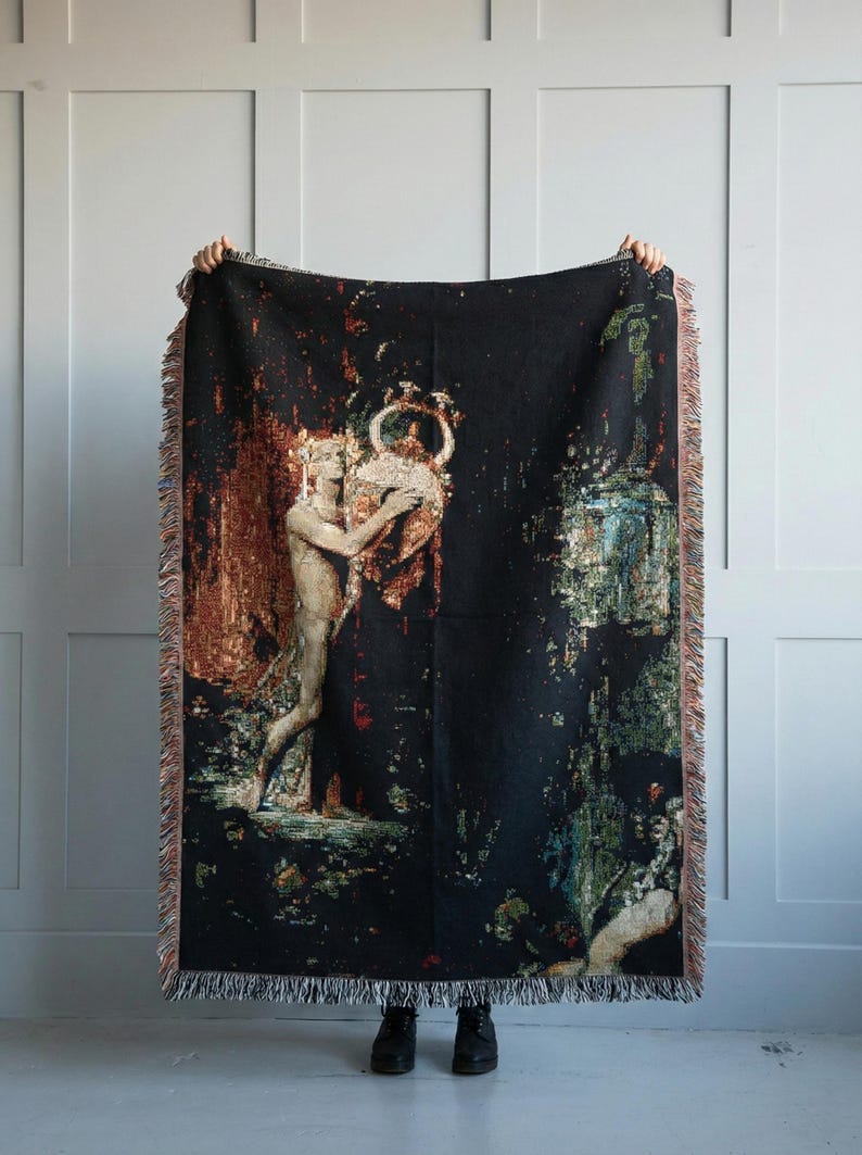 May include: A rectangular woven throw blanket with a black background featuring a detailed tapestry-style illustration of a figure holding a large ornate vessel. The design includes warm copper, gold, and deep green tones with a fringed edge.