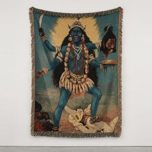K&ouml;nnte beinhalten: Eine gewebte Wandteppichdecke mit einer blauh&auml;utigen Figur mit vier Armen, die eine Krone und eine Totenkopfkette tr&auml;gt. Die Figur h&auml;lt ein Schwert und einen abgetrennten Kopf &uuml;ber einer Schale und steht auf einer liegenden Figur, mit Fransen.