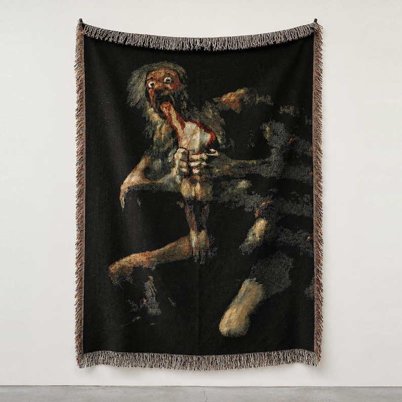 Pu&ograve; includere: Una coperta tessuta con una riproduzione di Saturno che divora suo figlio di Francisco Goya. L'arazzo scuro e strutturato mostra una figura dagli occhi sgranati che consuma una forma pi&ugrave; piccola su sfondo nero, con bordi sfrangiati.