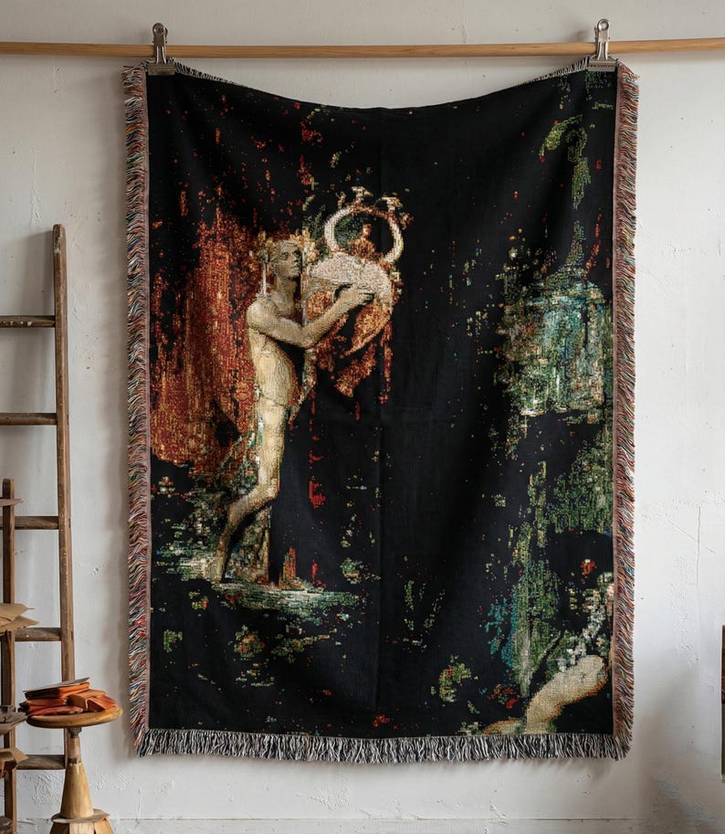 May include: A rectangular woven throw blanket featuring a black background with a central illustration of a figure holding a large vessel. The design incorporates warm orange, red, and cool green tones with fringed edges on all four sides.