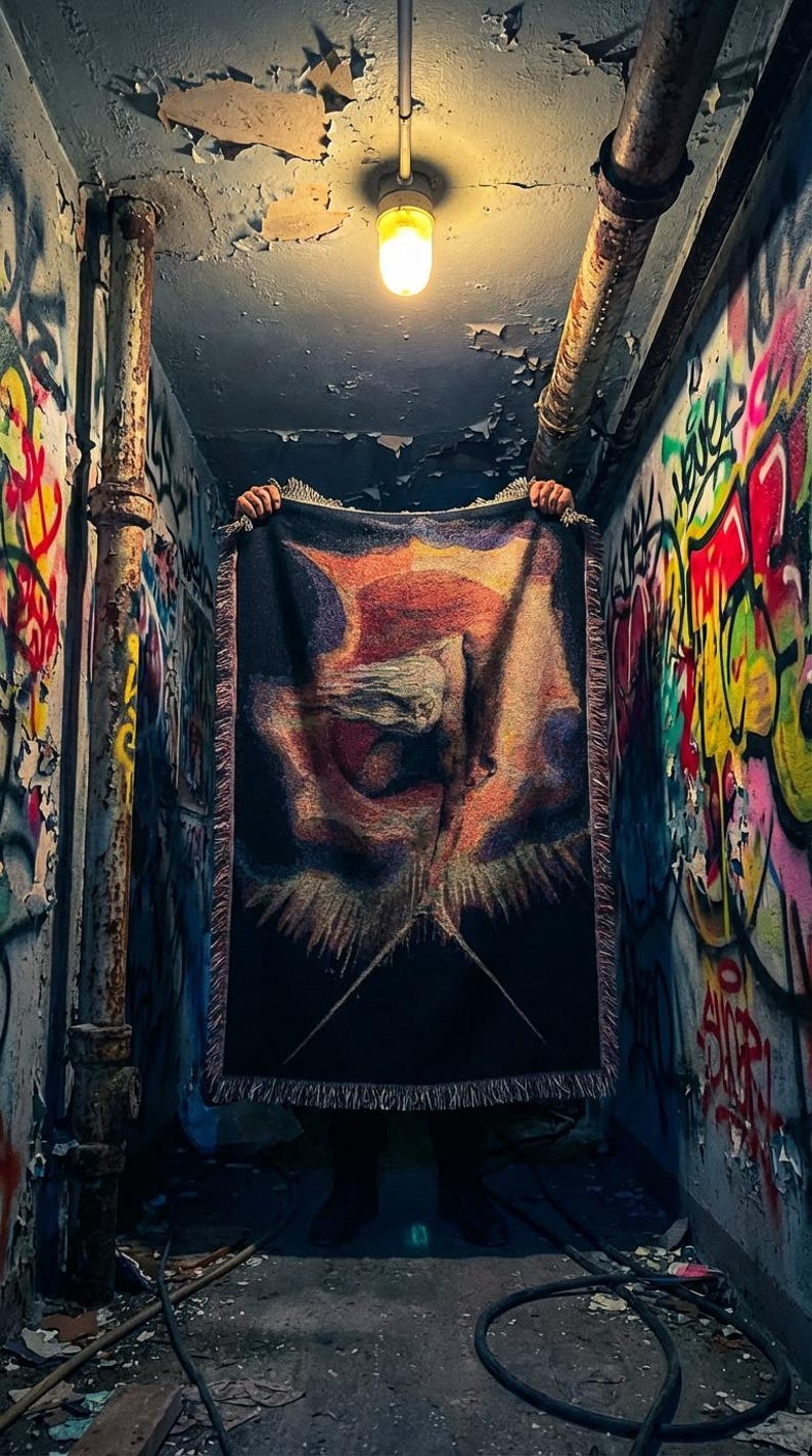 Puede incluir: Una manta tejida rectangular con un fondo oscuro y un dise&ntilde;o abstracto central en tonos naranja, amarillo y morado. La manta tiene un borde con flecos en todos sus lados y presenta una apariencia texturizada similar a un tapiz.