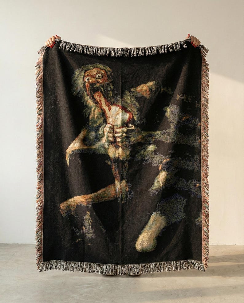 Pu&ograve; includere: Una coperta in tessuto nero con una riproduzione dettagliata del dipinto Saturno che divora i suoi figli di Francisco Goya. La coperta rettangolare presenta una superficie testurizzata e bordi con frange decorative lungo i lati.