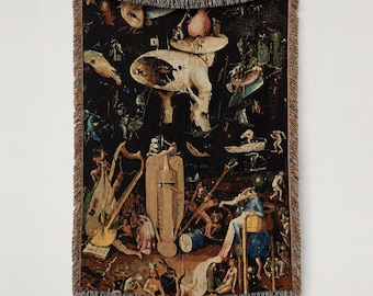 Puede incluir: Una manta tejida que presenta una reproducción detallada del panel del Infierno de El jardín de las delicias de El Bosco, con tonos oscuros, figuras surrealistas complejas, un arpa y una estructura central de madera.