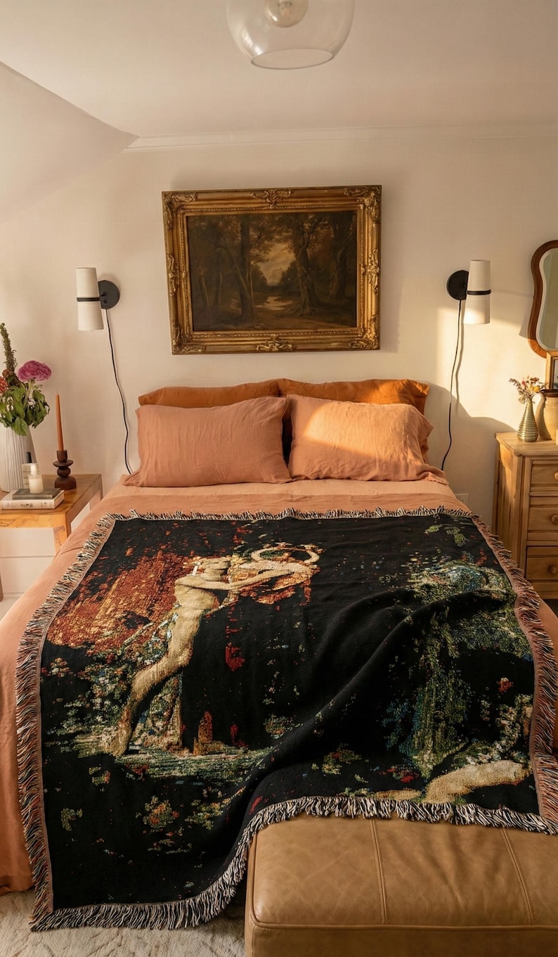 May include: A rectangular woven throw blanket featuring a dark black background with a detailed, colorful tapestry-style illustration of a figure holding a circular object amidst a landscape of trees and foliage, finished with fringed edges.