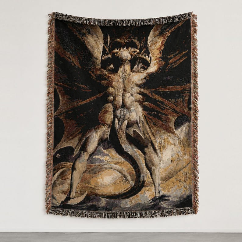 Puede incluir: Una manta tejida que presenta una ilustraci&oacute;n oscura y detallada de una figura alada y musculosa con cola, sobre un fondo negro con reflejos de color marr&oacute;n dorado y un borde decorativo con flecos en los cuatro lados del tejido rectangular.