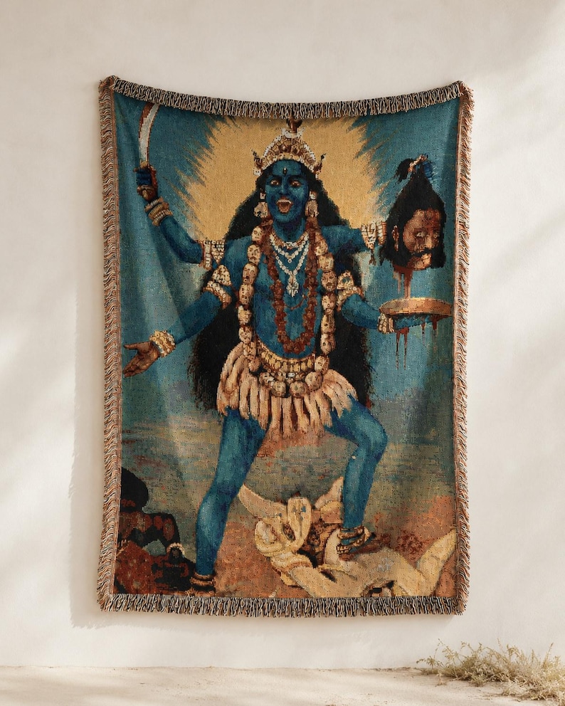 K&ouml;nnte beinhalten: Eine gewebte Wohndecke mit einer blauh&auml;utigen Figur mit mehreren Armen, die eine Krone und eine Totenkopfkette tr&auml;gt. Die Figur h&auml;lt ein Schwert und einen abgetrennten Kopf &uuml;ber einer Schale und steht auf einer liegenden Figur, mit Fransen an den R&auml;ndern.