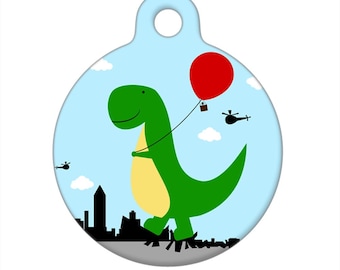 Può includere: Un'etichetta rotonda per animali domestici di colore azzurro chiaro con un dinosauro verde che tiene in mano un palloncino rosso. Il dinosauro cammina su uno skyline con elicotteri nel cielo. L'etichetta ha un foro.