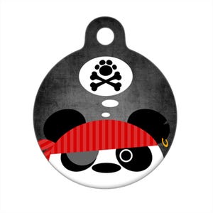 May include: A round black and white dog tag featuring a panda wearing a red and white striped eye patch and a gold earring. The panda is thinking about a white skull and crossbones with paw prints inside a circle.
