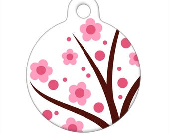 Könnte beinhalten: Runder weißer Haustieranhänger mit einem braunen Baumzweigdesign und rosa Blüten.