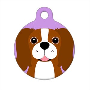 May include: A round purple dog tag with a cartoon image of a brown and white dog with big brown eyes. The dog is smiling with its tongue sticking out.