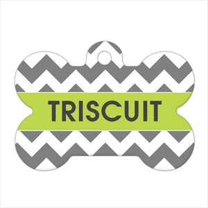 May include: A gray and white chevron patterned bone-shaped dog tag with a green band that says "TRISCUIT" in black.