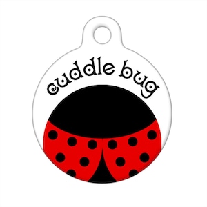 Puede incluir: Etiqueta redonda blanca para mascotas con un diseño de mariquita negra y roja. La etiqueta dice "cuddle bug" en un círculo negro alrededor de la mariquita.