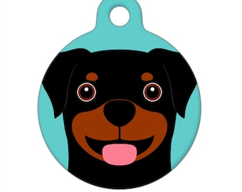 May include: A round, turquoise blue dog tag with a black and brown Rottweiler dog face. The dog has a pink tongue sticking out and big, round eyes.