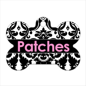 May include: Black and white damask patterned dog bone tag with the name "Patches" in pink lettering.