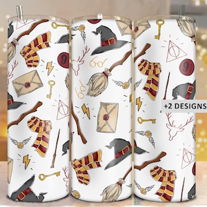May include: Three white insulated tumblers with a repeating pattern of wizarding school themed illustrations. The design includes a black hat, broom, scarf, key, and lightning bolt. The tumblers have a silver straw and the text "+2 DESIGNS".