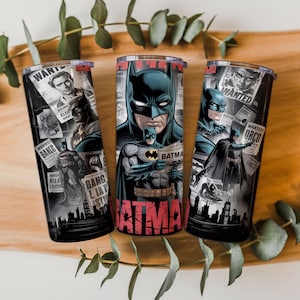 Op de afbeelding: Drie roestvrijstalen bekers met Batman-ontwerpen. De ontwerpen bevatten afbeeldingen van Batman, stripboekpanelen en het Batman-logo. De bekers hebben een zwarte achtergrond met rode en witte accenten. De bekers zijn cilindrisch en hebben een deksel.